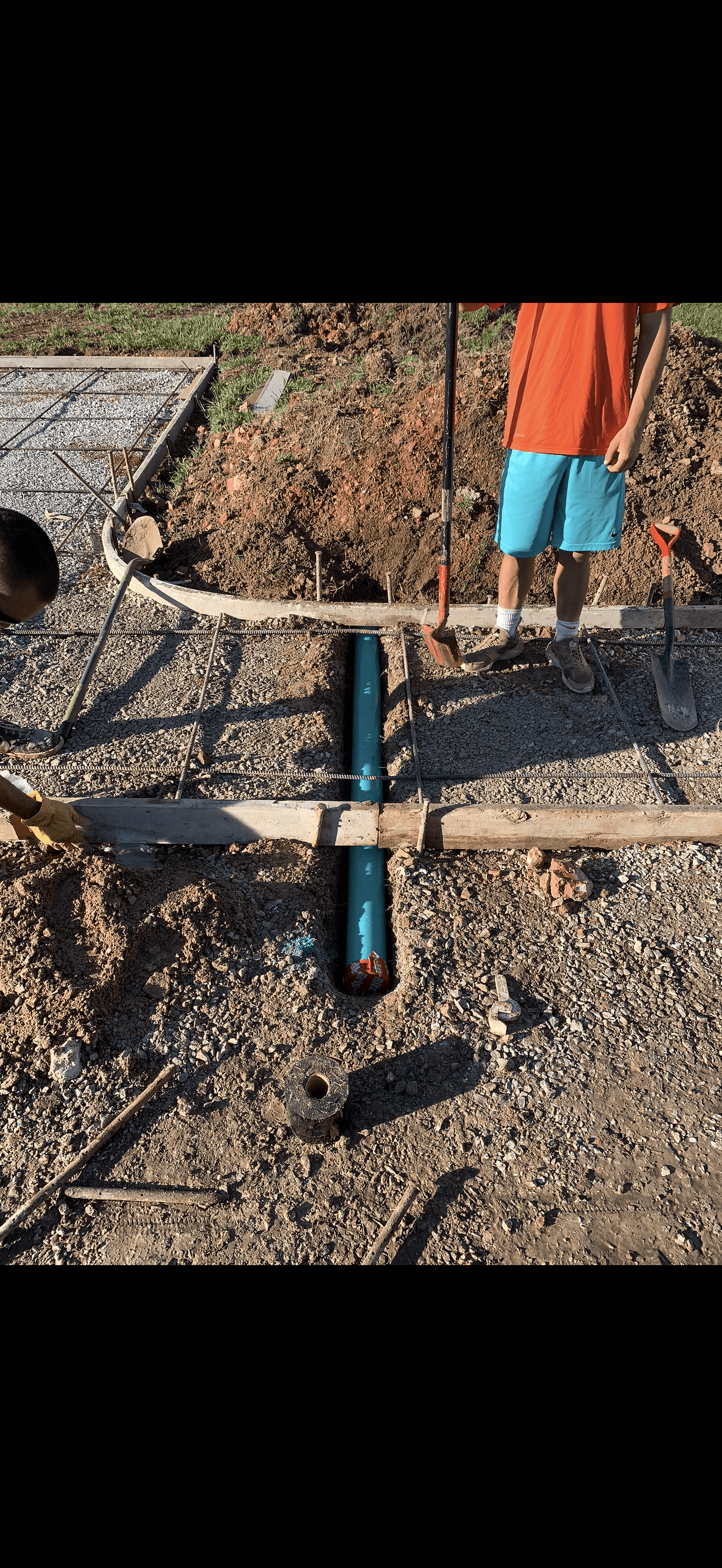Blue PVC pipe in a trench under rebar and forms for a concrete slab.